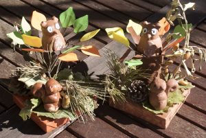 écureuil et hibou en plâtre dans un décor d'automne avec des feuilles et une pomme de pin